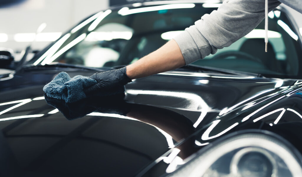 A car being meticulously wiped down with a microfiber cloth by Detailing World, showcasing the finishing touches of a professional car wash.